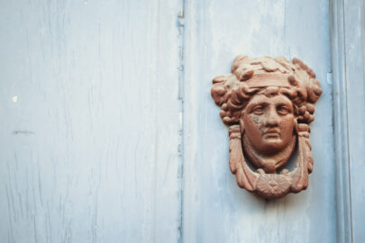 Decorated face door knob made of metal on a blue wooden door - slon.pics - free stock photos and illustrations