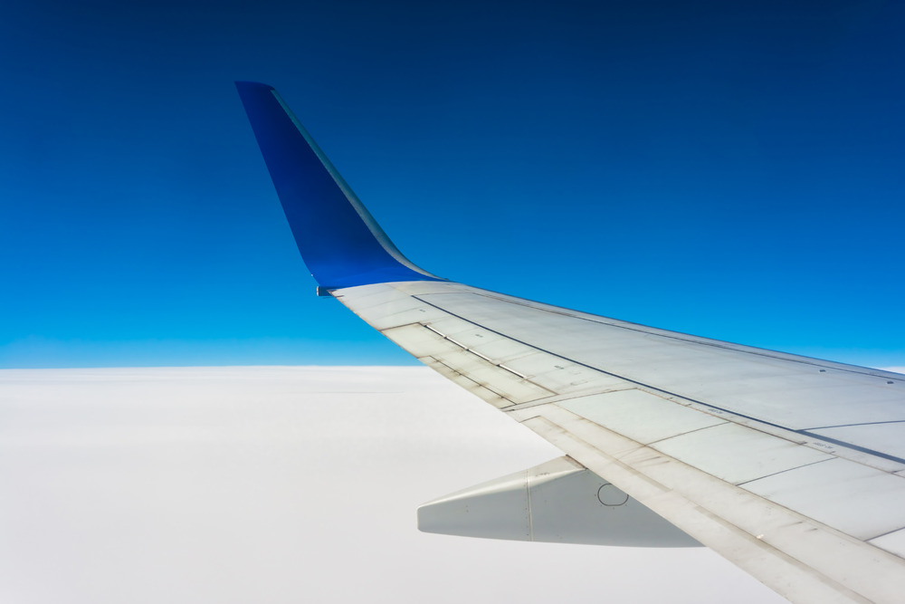 Airplane wing over white clouds
