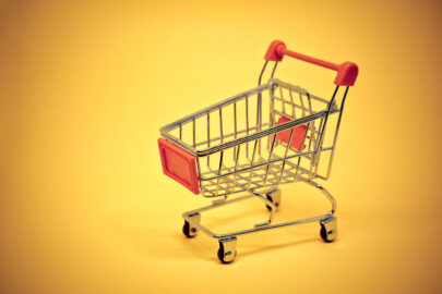Miniature shopping cart on yellow background - slon.pics - free stock photos and illustrations