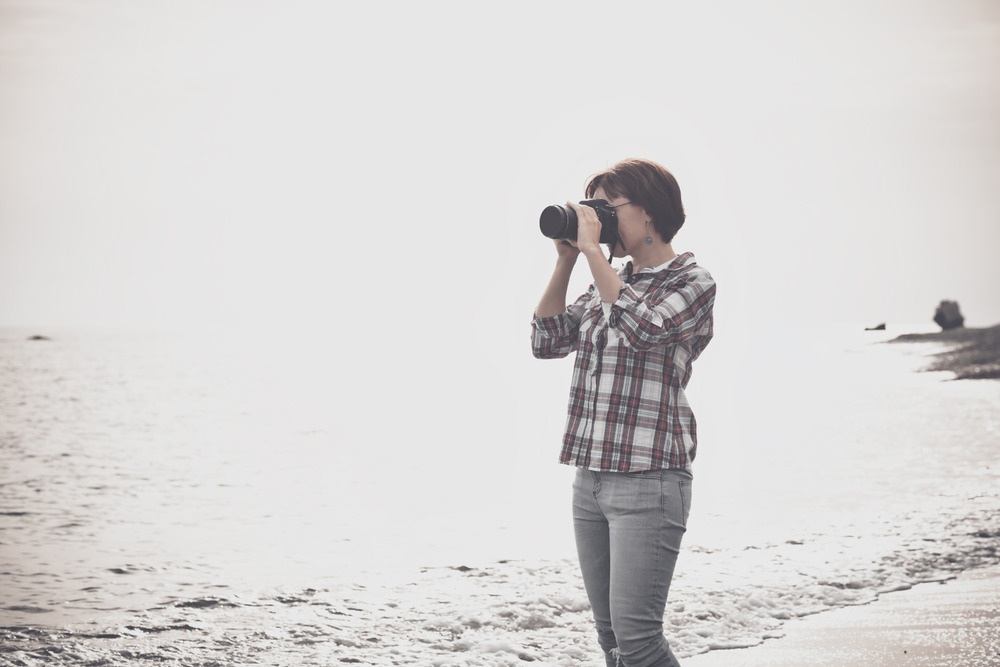 Woman taking photographs with DSLR on the beach